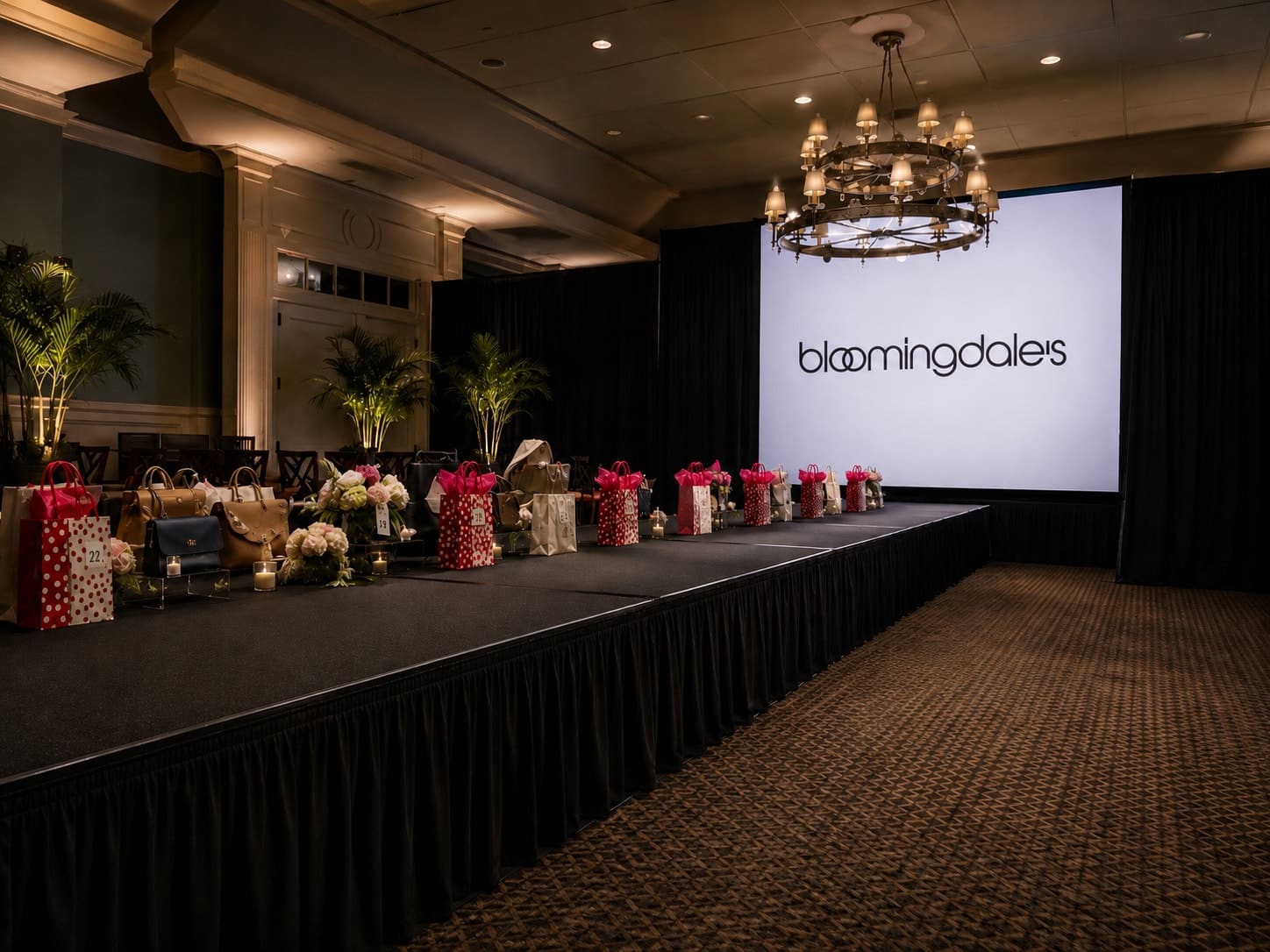 Branded Bloomingdale's fashion show runway with chandelier and presentation screen in a ballroom