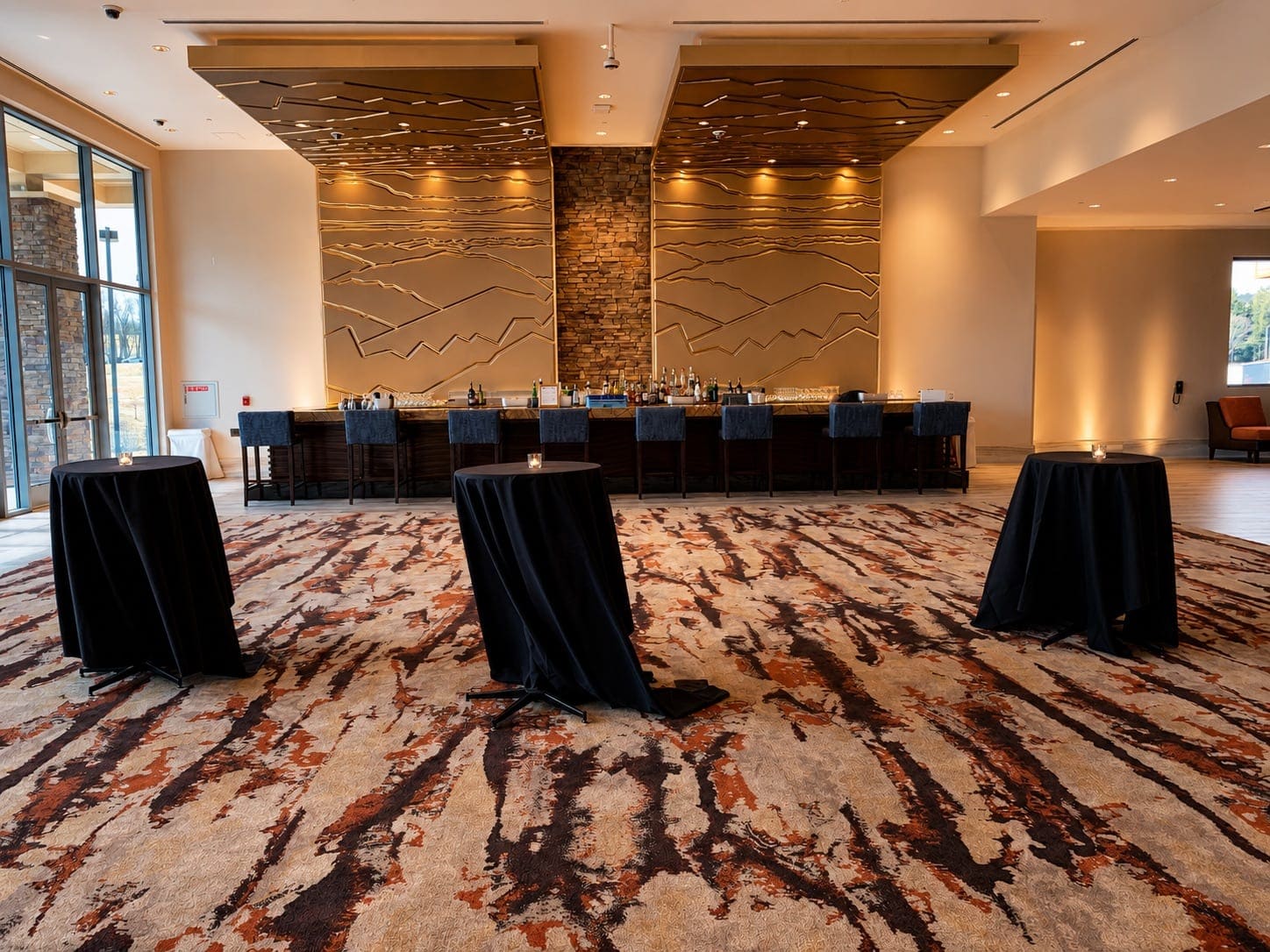 Pre-function bar and cocktail tables lit with amber uplighting at a corporate reception