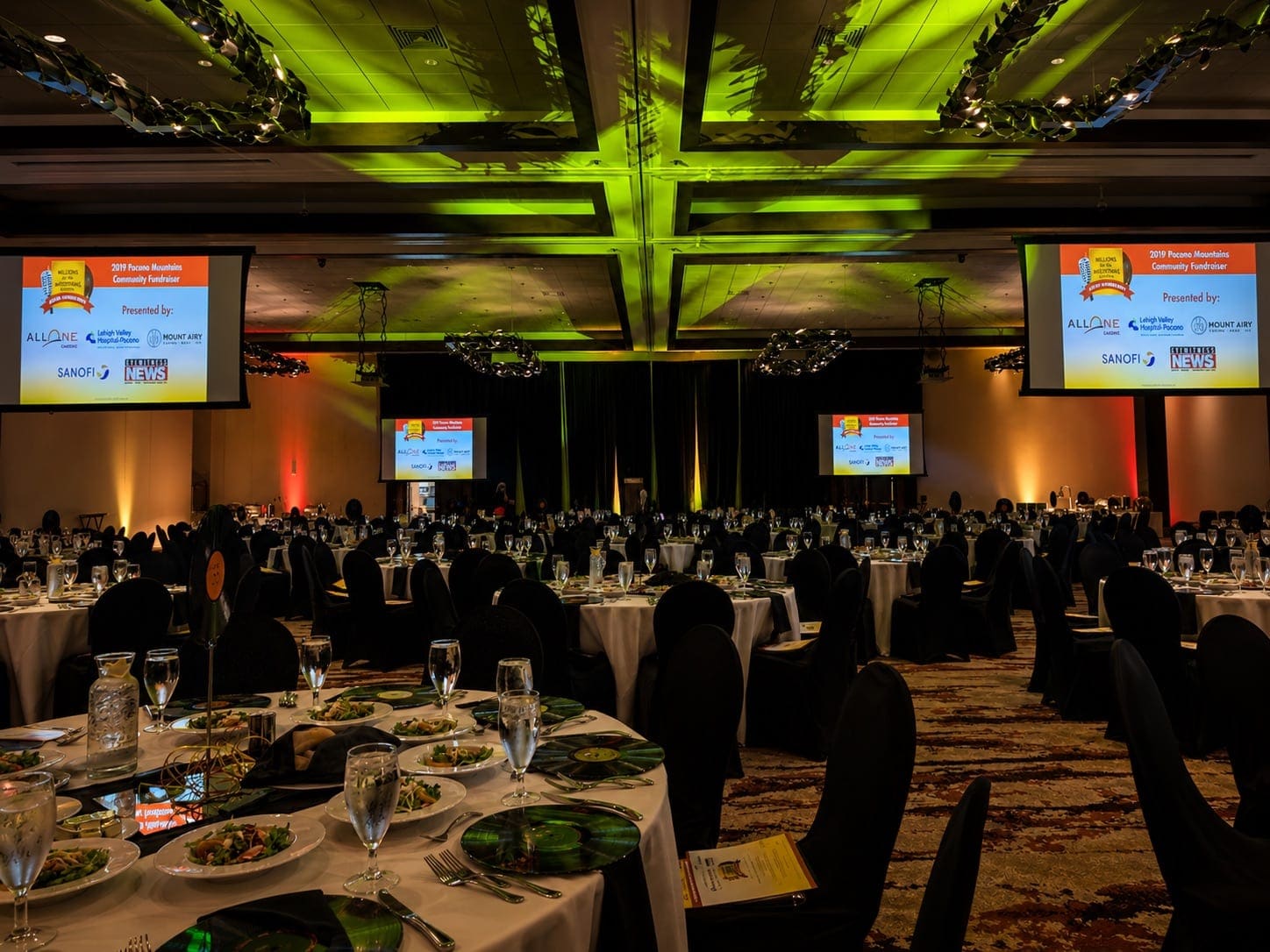 Gala dinner with green gobo ceiling wash and twin projection screens carrying sponsor branding