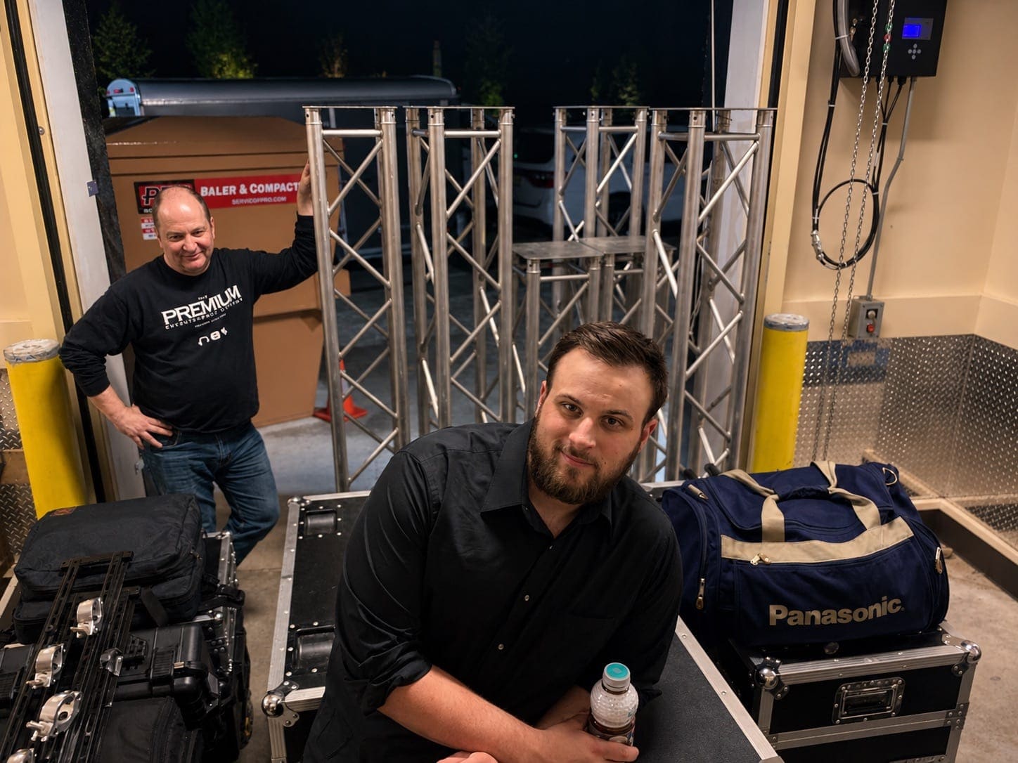 PremiumAVC crew at load-in with truss sections, road cases, and rigging gear backstage